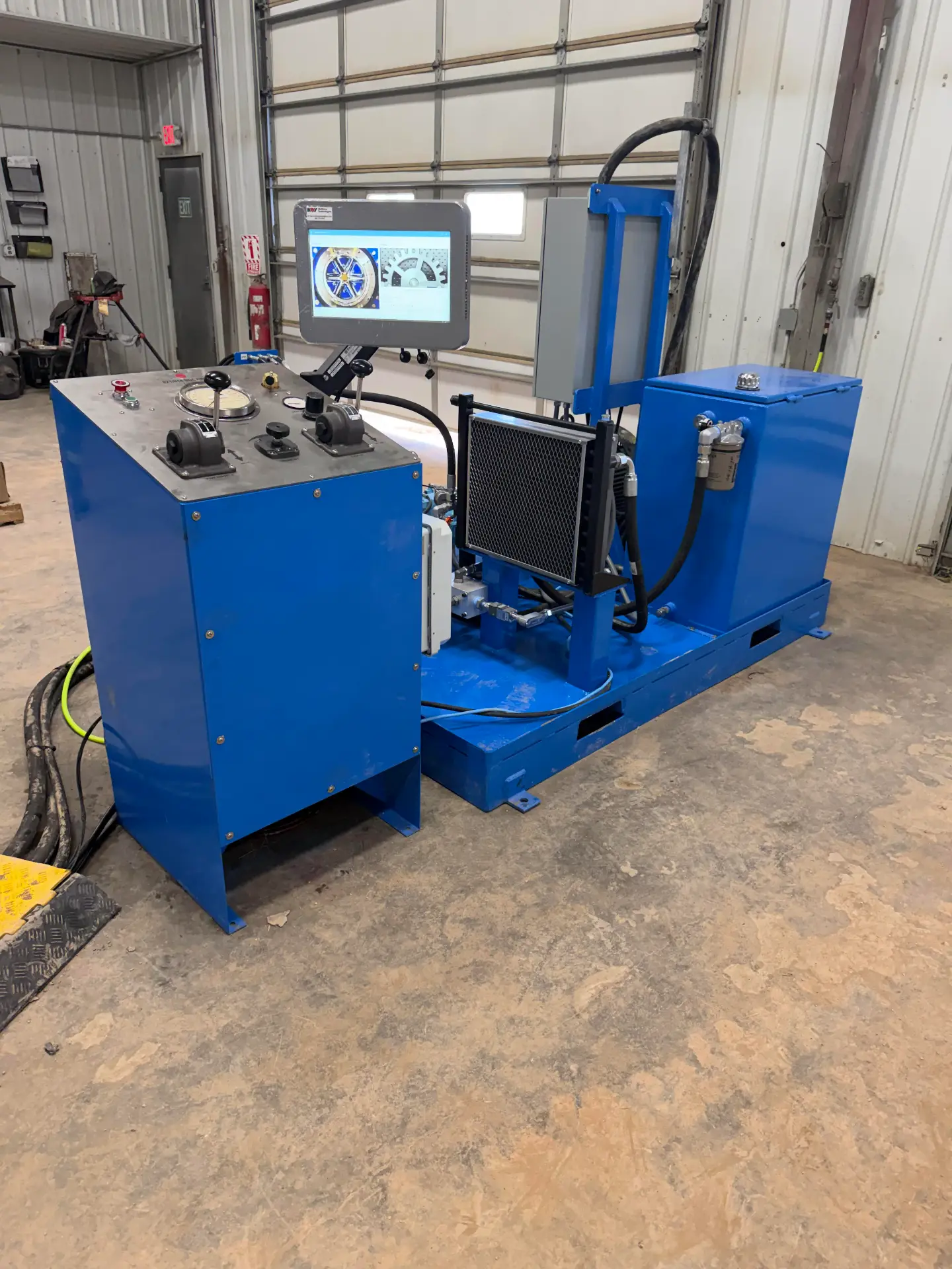 Blue NOV bucking unit control stand and hydraulic power pack staged in the WOS shop