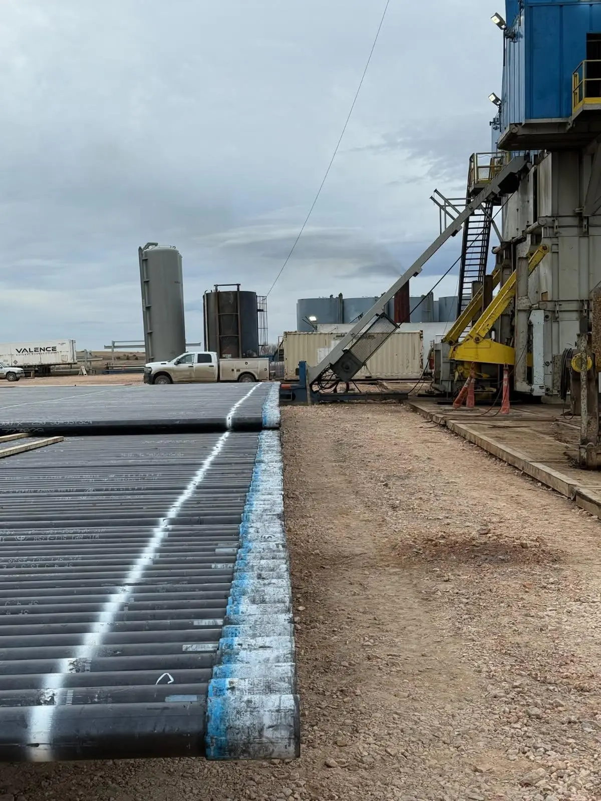 Casing pipe staged next to a workover rig in a Bakken yard