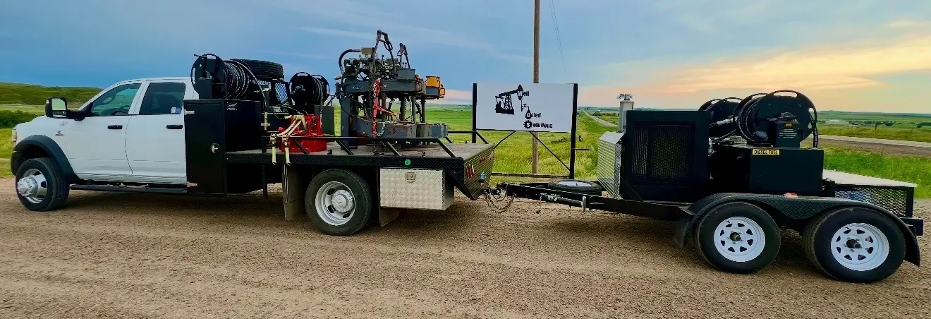 WOS truck and trailer with hydraulic power unit staged on a Bakken road at sunset