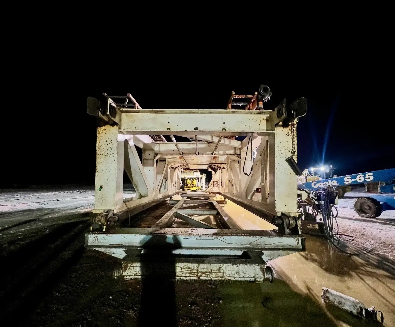 Rig substructure under a Genie boom lift being pressure washed at night