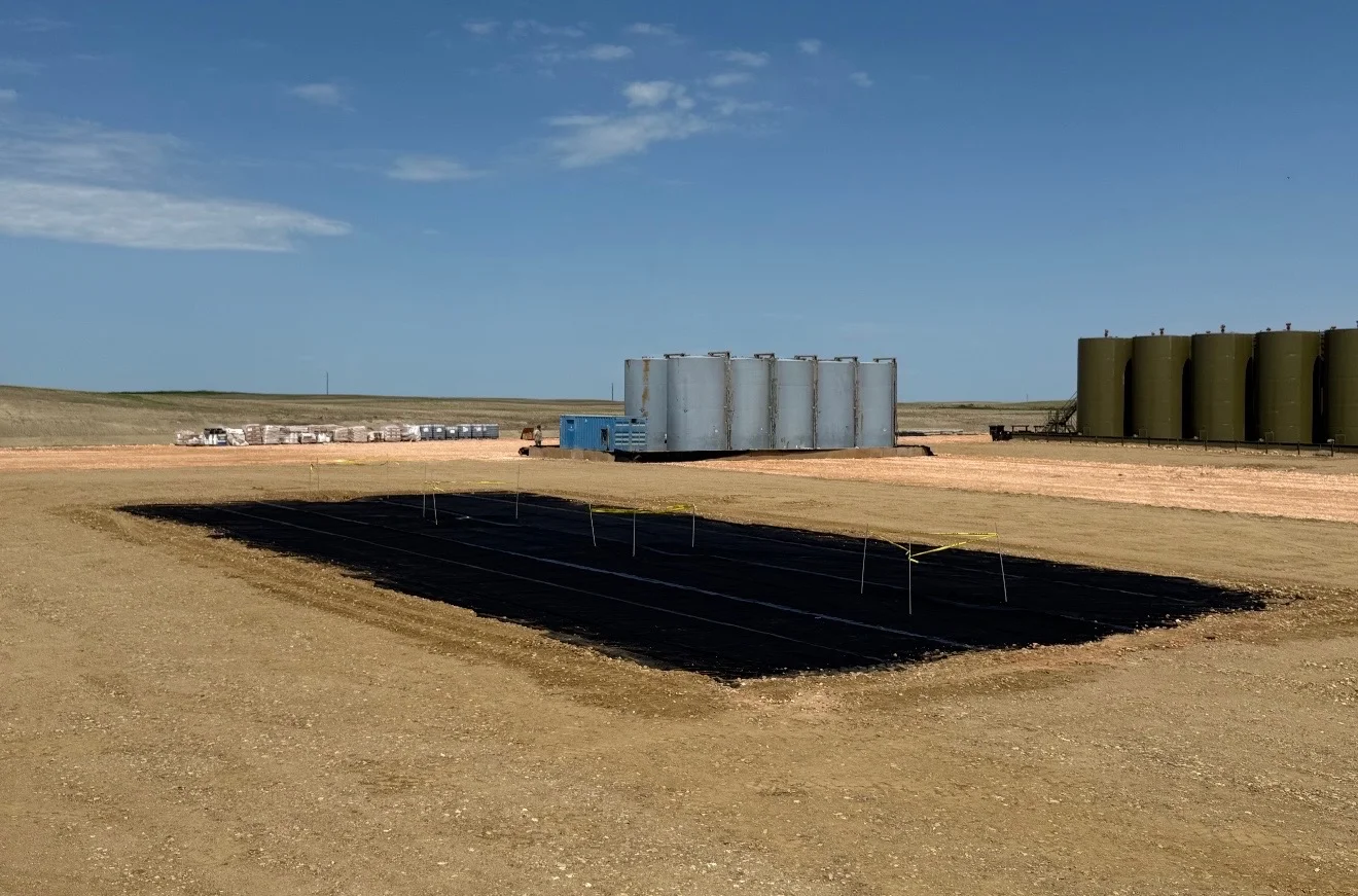 Freshly built drilling location with tank battery, doghouse, and rig matting on a Bakken pad