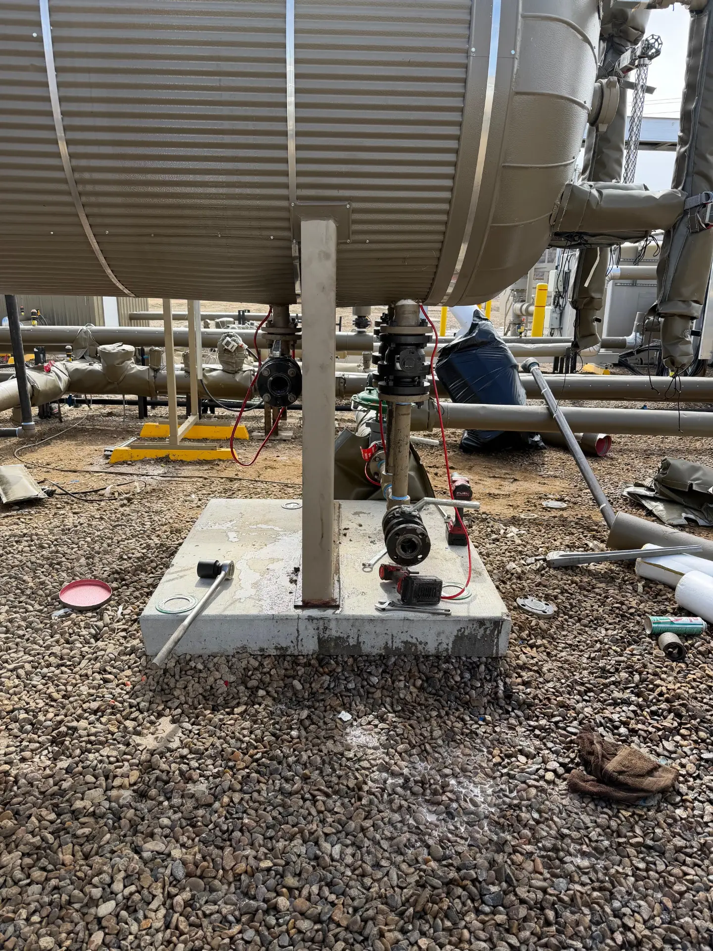 Pipe spool, valve, and impact tools staged on a treater base during Bakken facility repair work