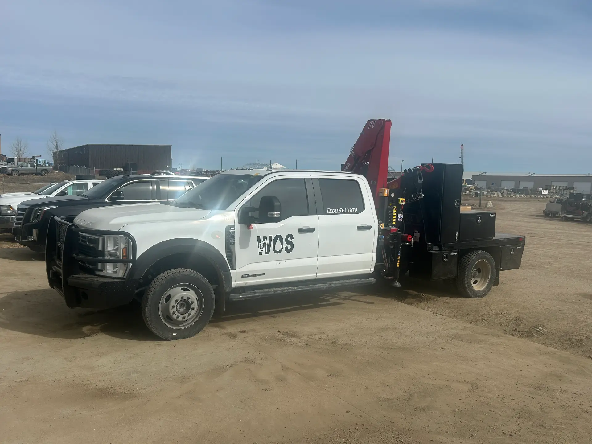 White WOS Ford F-550 roustabout truck with a red Hiab knuckle boom crane and flat bed at the yard