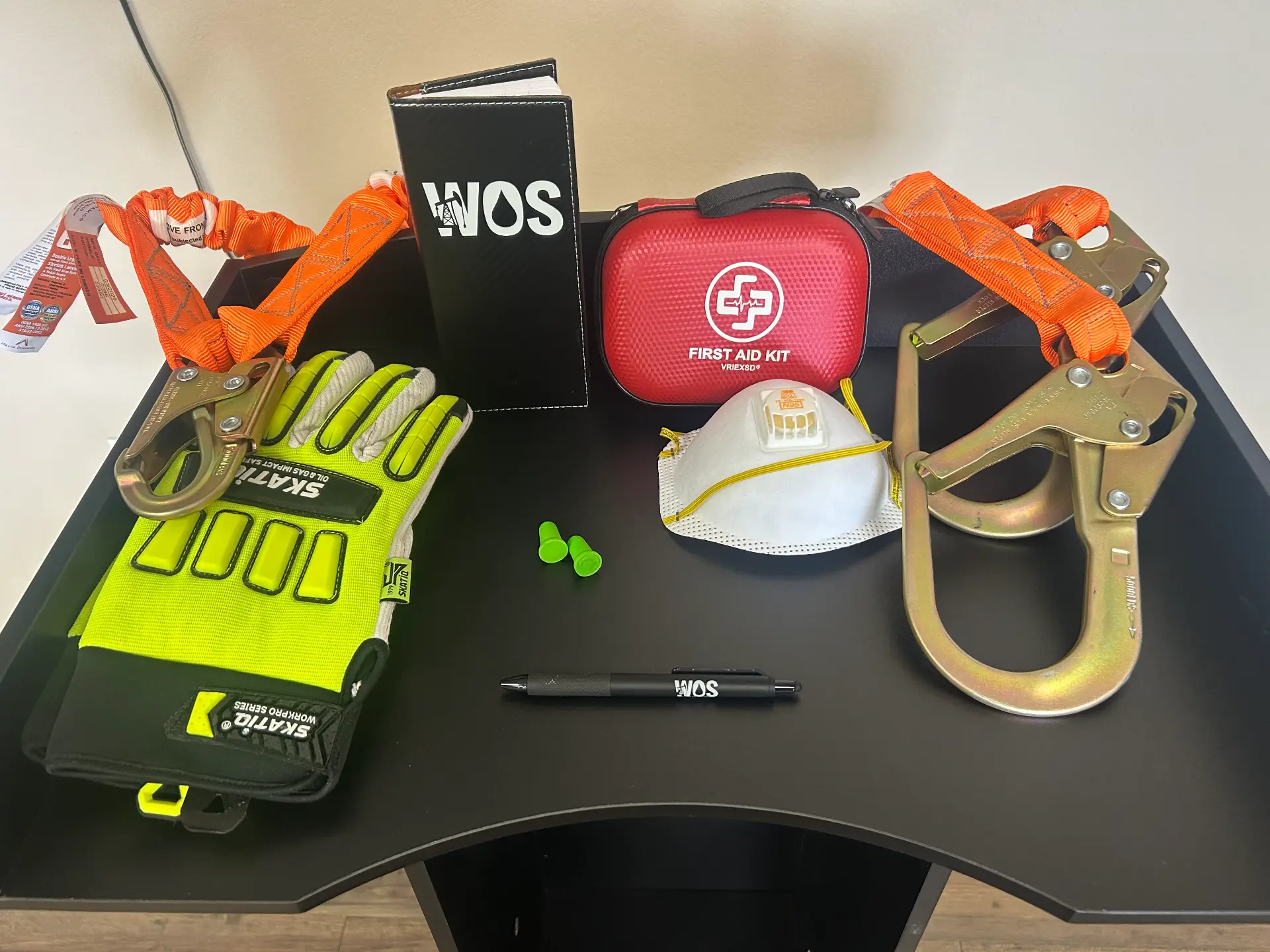 WOS-branded safety kit including gloves, harness clips, first aid kit, respirator, ear plugs, and HSE manual